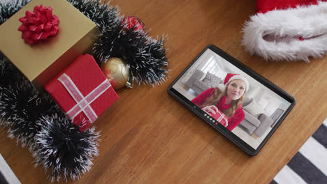 Smiling-caucasian-woman-wearing-santa-hat-on-christmas-video-call-on-tablet