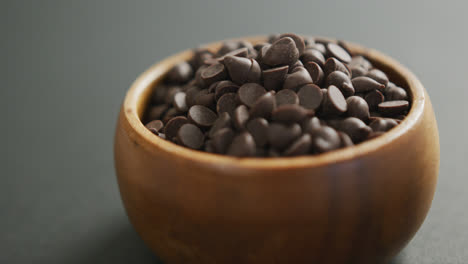 Video-of-close-up-of-wooden-bowl-of-chocolate-chip-over-grey-background