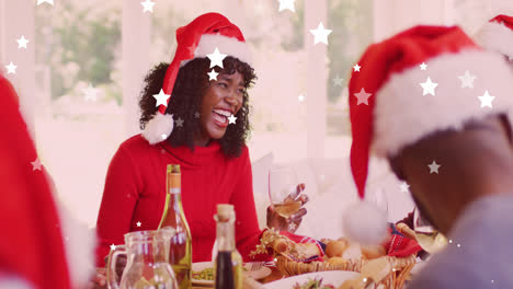 Animation-of-stars-falling-over-happy-african-american-family-wearing-santa-hats-and-having-dinner