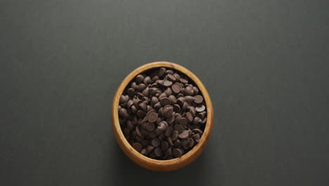 Video-of-overhead-view-of-wooden-bowl-of-chocolate-chip-over-grey-background