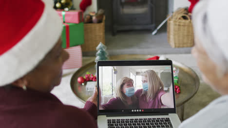 Diverse-senior-female-friends-using-laptop-for-christmas-video-call-with-family-on-screen