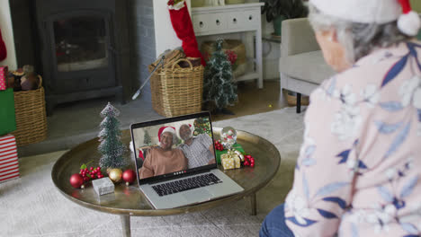 Senior-caucasian-woman-using-laptop-for-christmas-video-call-with-smiling-couple-on-screen