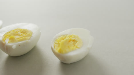 Video-of-close-up-of-three-halves-of-hard-boiled-eggs-on-grey-background