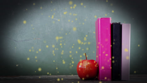 Animation-of-glowing-spots-over-apple-and-books-on-green-background