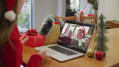 Caucasian-woman-on-laptop-video-call-with-happy-family-at-christmas-time