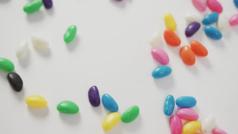 Video-of-close-up-of-multi-coloured-sweets-spinning-over-white-background