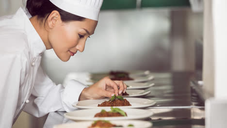 Smiling-asian-female-chef-wearing-apron-preparing-food-in-professional-kitchen