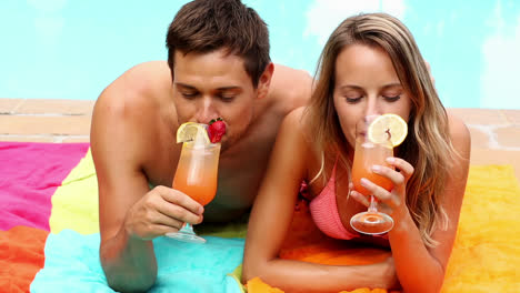 Pareja-Sexy-Tumbada-Junto-A-La-Piscina-De-Vacaciones-Bebiendo-Cócteles