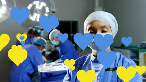 Animation-of-yellow-and-blue-hearts-floating-over-caucasian-female-surgeon-in-face-mask