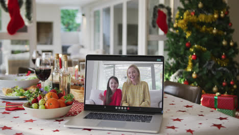 Happy-caucasian-mother-and-daughter-on-laptop-lying-on-christmas-table