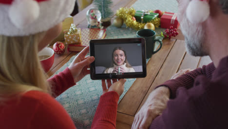 Kaukasisches-Paar-Mit-Weihnachtsmützen-Nutzt-Tablet-Für-Weihnachtsvideoanruf-Mit-Frau-Auf-Dem-Bildschirm