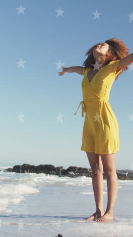 Animation-of-stars-over-african-american-woman-raising-hands-at-beach