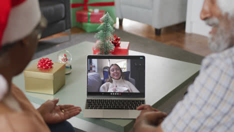 Happy-senior-african-american-couple-on-video-call-with-female-friend-at-christmas-time