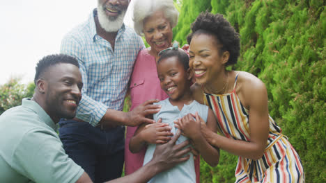 Portrait-of-happy-african-american-family-embracing-and-smiling-in-garden