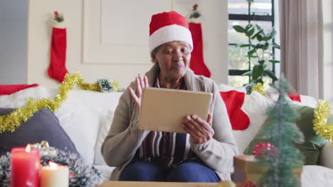 Fröhliche-Afroamerikanische-Seniorin-Mit-Weihnachtsmütze,-Die-Einen-Tablet-Videoanruf-Macht,-Zeitlupe