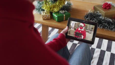 Albino-man-waving-and-using-tablet-for-christmas-video-call-with-santa-on-screen