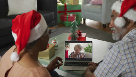 Feliz-Pareja-De-Ancianos-Afroamericanos-En-Una-Videollamada-Portátil-Con-Una-Amiga-En-Navidad