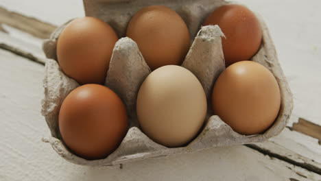 Video-of-overhead-view-of-brown-eggs-in-egg-carton-on-rustic-background