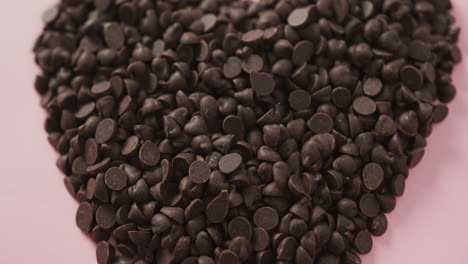Video-of-close-up-of-heart-formed-with-chocolate-chip-and-copy-space-over-pink-background