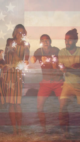 Animation-of-flag-of-united-states-of-america-over-happy-diverse-friends-with-sparklers-on-beach