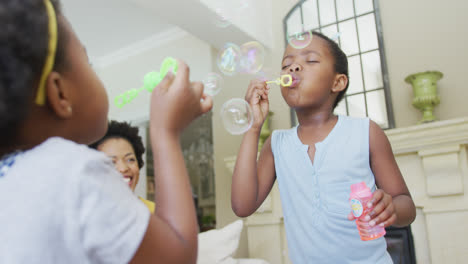 Glückliche-Afroamerikanische-Großmutter-Mit-Erwachsener-Tochter-Und-Enkelinnen,-Die-Seifenblasen-Pusten
