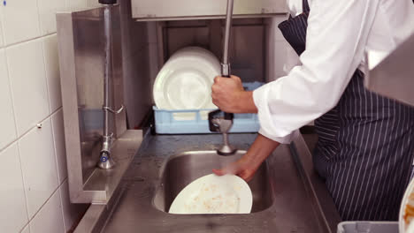 Kitchen-porter-cleaning-plates-in-sink
