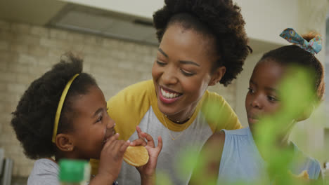 Glückliche-Afroamerikanische-Mutter-Mit-Töchtern-Beim-Essen-In-Der-Küche