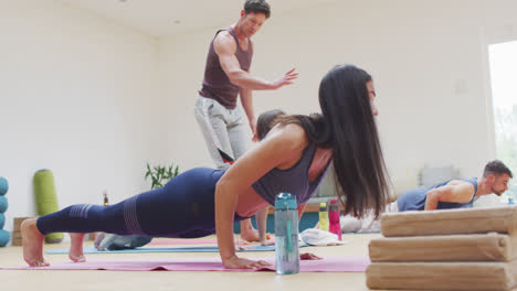 Vielfältige-Gruppe-übt-Yoga-Pose-Im-Unterricht-Mit-Männlichem-Lehrer,-Der-Hilft