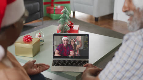 Happy-african-american-senior-couple-on-laptop-video-call-with-family-at-christmas-time