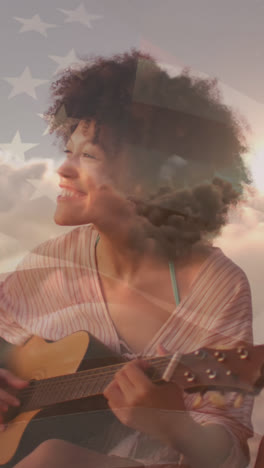 Animation-of-flag-of-united-states-of-america-over-happy-biracial-woman-playing-guitar-on-beach
