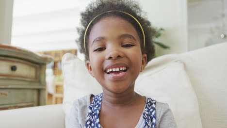 Porträt-Eines-Lächelnden-Afroamerikanischen-Mädchens,-Das-Im-Wohnzimmer-In-Die-Kamera-Blickt