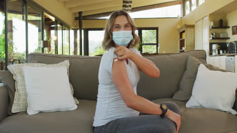 Caucasian-pregnant-woman-in-face-mask-showing-arm-with-plaster-after-vaccination