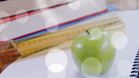 Animation-of-white-spots-over-apple-and-books