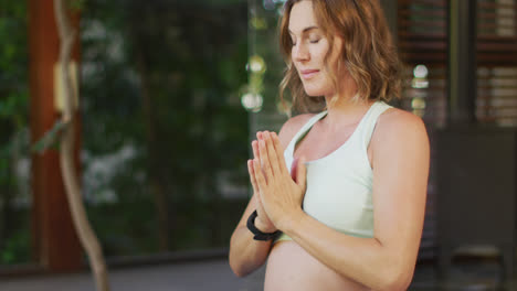 Entspannte-Kaukasische-Schwangere-Frau-Praktiziert-Yoga-Auf-Der-Terrasse