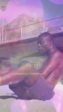 Lichtpunkte-Vor-Einem-Fitten-Afroamerikanischen-Mann,-Der-Am-Strand-Übungen-Mit-Einem-Medizinball-Durchführt