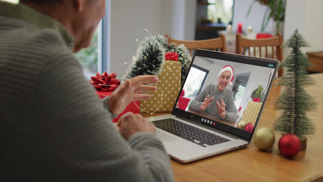 Caucasian-senior-man-having-christmas-video-call-on-laptop-with-caucasian-senior-male-friend