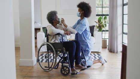 African-american-female-doctor-giving-oxygen-to-senior-female-patient-in-wheelchair,-slow-motion