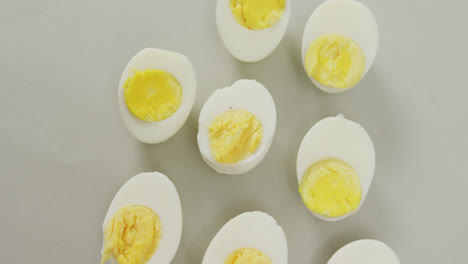 Video-of-overhead-view-of-halves-of-hard-boiled-eggs-on-grey-background