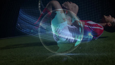 Animation-of-globe-rotating-with-lights-over-injured-caucasian-male-soccer-player