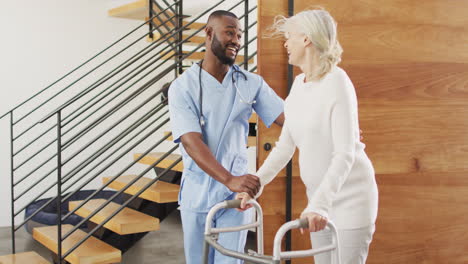 Young-African-American-male-nurse-assists-senior-Caucasian-woman-at-home
