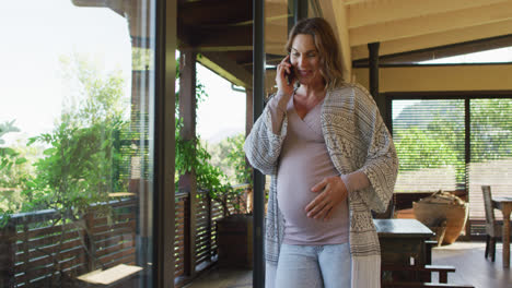 Happy-caucasian-pregnant-woman-standing-on-patio-and-having-phone-call