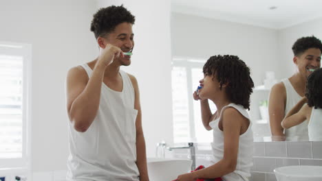Biracial-father-and-son-brush-their-teeth-together-at-home