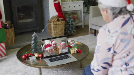 Ältere-Kaukasische-Frau-Benutzt-Laptop-Für-Weihnachtsvideoanruf-Mit-Lächelnder-Familie-Auf-Dem-Bildschirm