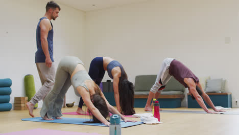 Grupo-Diverso-Practicando-Pose-De-Yoga-En-Clase-Con-Un-Instructor-Masculino-Ayudando