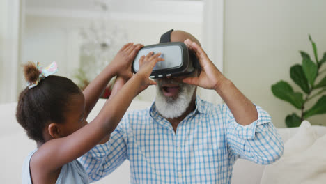 Glücklicher-Afroamerikanischer-Großvater-Mit-VR-Headset-Und-Enkelin-Im-Wohnzimmer