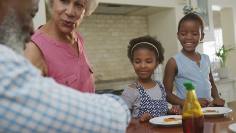 Happy-african-american-grandparents-with-granddaughters-having-breakfast-and-talking