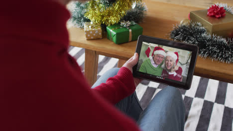 Albino-man-waving-and-using-tablet-for-christmas-video-call-with-smiling-couple-on-screen