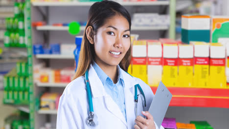 Animation-of-smiling-asian-female-doctor-with-clipboard-over-pharmacy