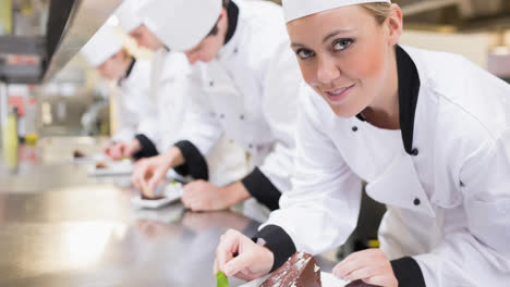 Smiling-caucasian-female-chef-wearing-apron-preparing-food-in-professional-kitchen