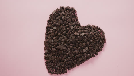 Video-Eines-Herzens-Aus-Schokoladenstückchen-Und-Kopierraum-Auf-Rosa-Hintergrund